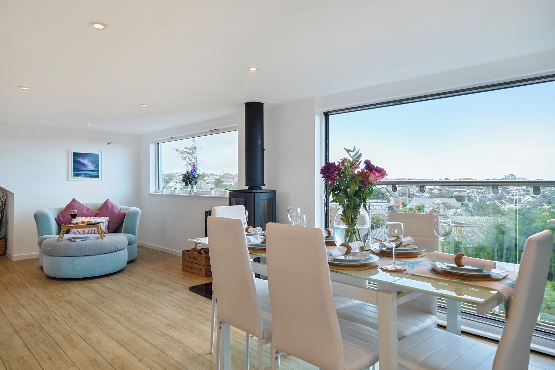 A modern living room with a dining area, a fireplace, and large windows offering a city view.