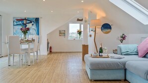 Ein modernes Wohnzimmer mit Essbereich, Holzböden, einer Loft-Decke und Blick auf die Stadt.