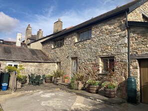 A stone building with a courtyard, wooden shutters, and potted plants. - Old Armoury Barn (Newton Abbot)