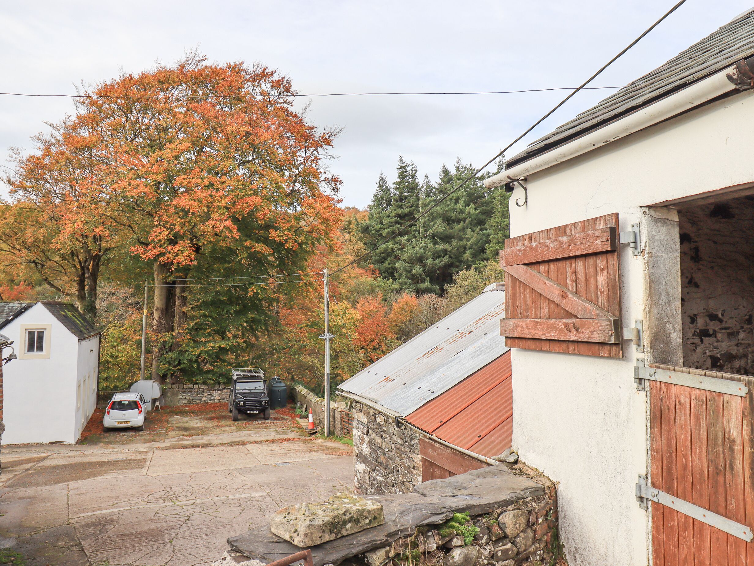 A rustic building with a stone wall, a wooden door, and a car parked in front.