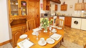 Een traditionele keuken met houten kastjes, een eettafel voor vier personen en een wasmachine.
