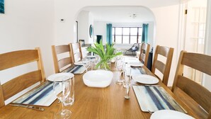 Un coin repas avec une table en bois dressée pour six personnes, entourée de chaises en bois.