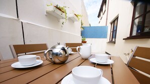 Une table en bois avec des tasses et des soucoupes blanches, ainsi qu’une théière en argent.