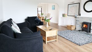 Un salon moderne avec un canapé noir, une table basse en bois et une cheminée.