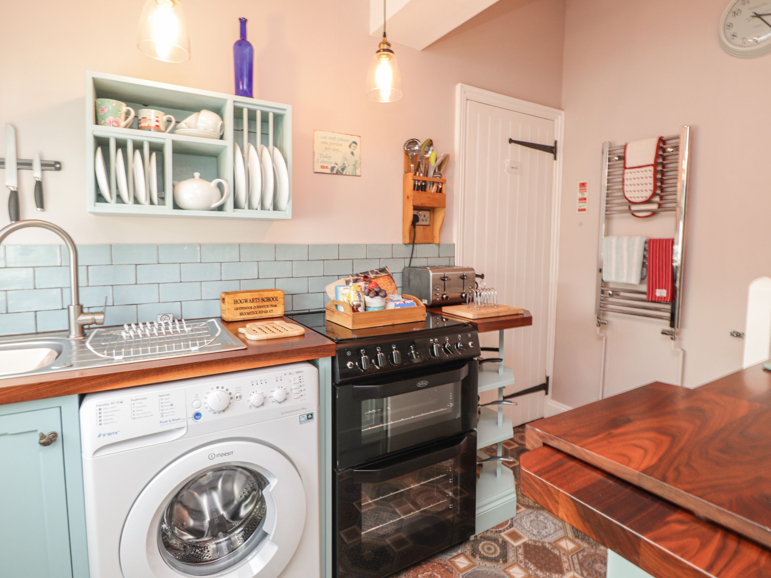 Une cuisine compacte équipée d’un lave-linge, d’un four et d’un plan de travail en bois.