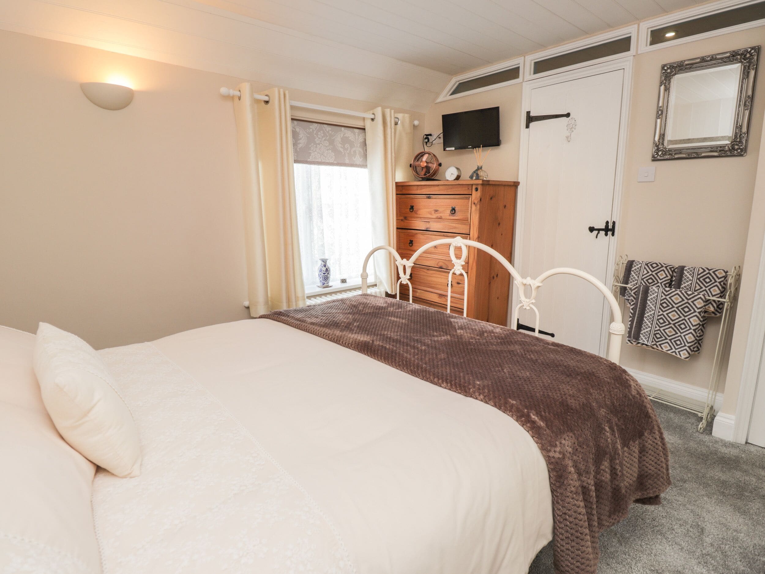 Un dormitorio con cama, cómoda, espejo y televisor.