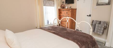 Un dormitorio con cama, cómoda, espejo y televisor.