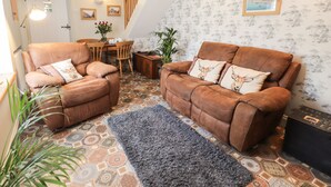 Una sala de estar acogedora con dos sofás marrones, un tapete estampado y un comedor con muebles de madera.