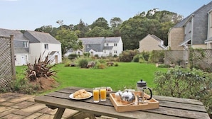 A picnic table with breakfast items, a grassy backyard, and houses in the background. - Chyandour (Falmouth)