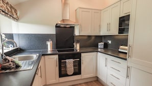 A kitchen with a sink, stove, oven, and cabinets.