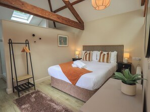 A bedroom with a bed, bedside tables, a hanging rack, a skylight, and a plant. - Acorn (Ambleside)
