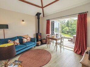 A cozy living room with a sofa, a table, chairs, a fireplace, and a view of the outdoors.