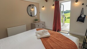 A bedroom with a bed, a dresser, a mirror, a window with curtains, and a view of the outdoors.