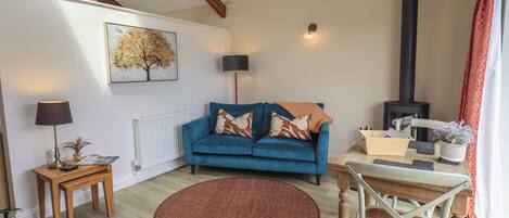 A cozy living room with a blue sofa, a round rug, a wooden table, and a fireplace.