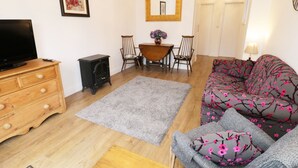 A cozy living room with a sofa, a TV, a fireplace, and a dining area. - Foxes Den (Thornton-Cleveleys)