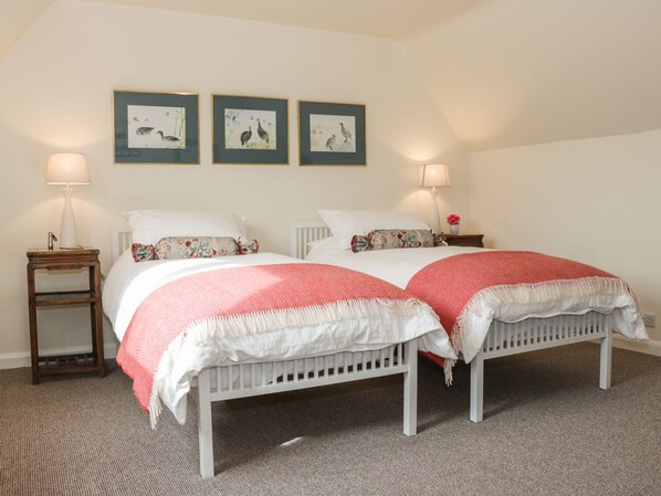 A bedroom with two beds, a nightstand with a lamp, and three framed pictures on the wall. - Lower Hodre (Bucknell)