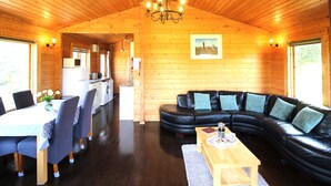 Interior acogedor de una cabaña con comedor, sala de estar con sofá y área de cocina.
