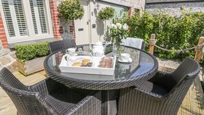 A round glass table with wicker chairs, a tray with pastries, and a teapot. - Oh Buoy! (St Austell)
