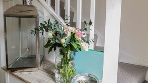 A staircase with a clear glass vase of flowers on a wooden ledge. - Oh Buoy! (St Austell)