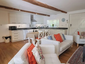 Eine moderne Küche mit weißen Schränken, einem Esstisch und einem weißen Sofa mit bunten Kissen.