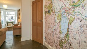 Una habitación con un mapa grande en la pared, una puerta de madera y una zona de estar con una lámpara.