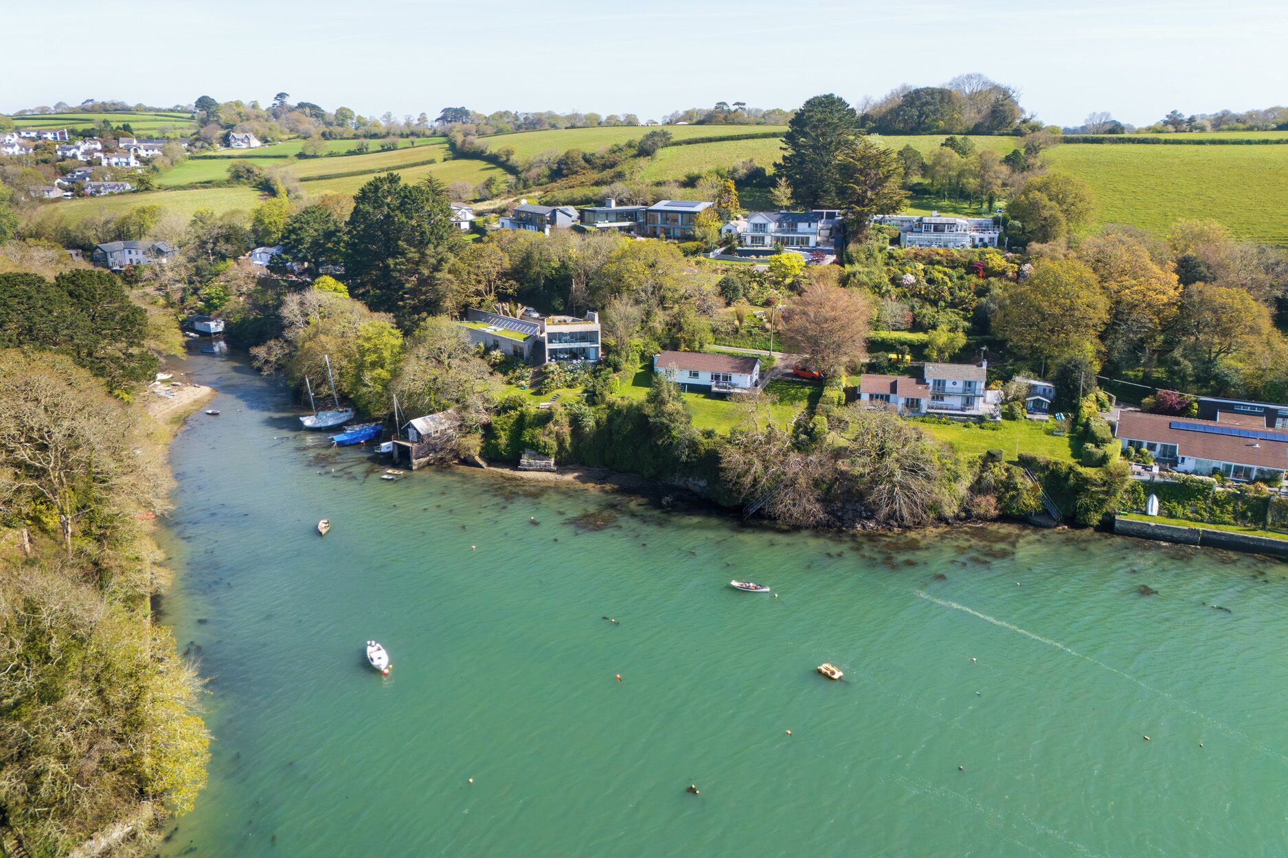 A riverside village with houses, boats, and greenery.