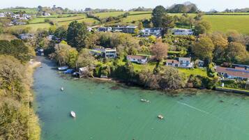 A riverside village with houses, boats, and greenery.