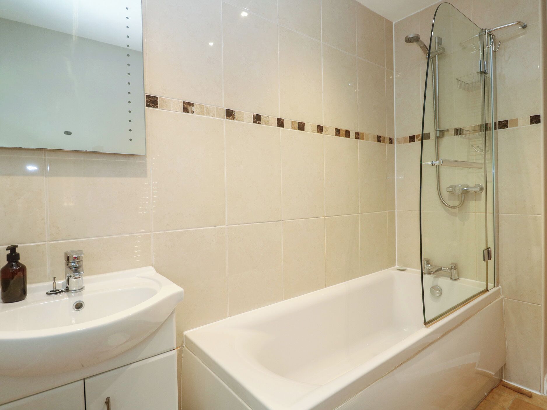Une salle de bain équipée d’un lavabo, d’un miroir et d’une douche à parois de verre.