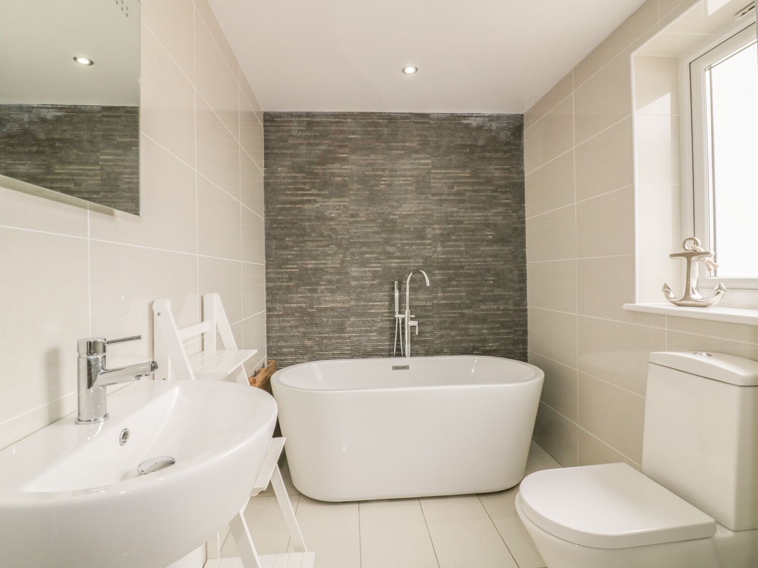 Ein modernes Badezimmer mit freistehender Badewanne, Waschbecken und Toilette.