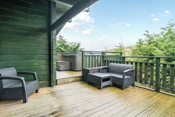 A wooden deck with outdoor furniture, including two chairs and a sofa, and a hot tub. - Elm Lodge (Ulverston)