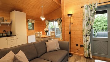 A cozy cabin interior with a sofa, dining table, and a kitchen area.