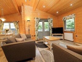 Un interior de cabaña acogedor con un sofá, una mesa de centro, un televisor y una zona de comedor.
