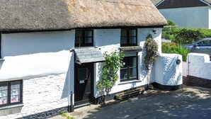 A traditional white building with a thatched roof, a black door, and a small window.