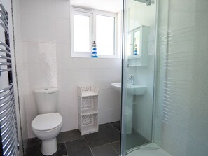 A bathroom with a toilet, a glass-enclosed shower, and a sink. - Easterly Cottage (Bude)