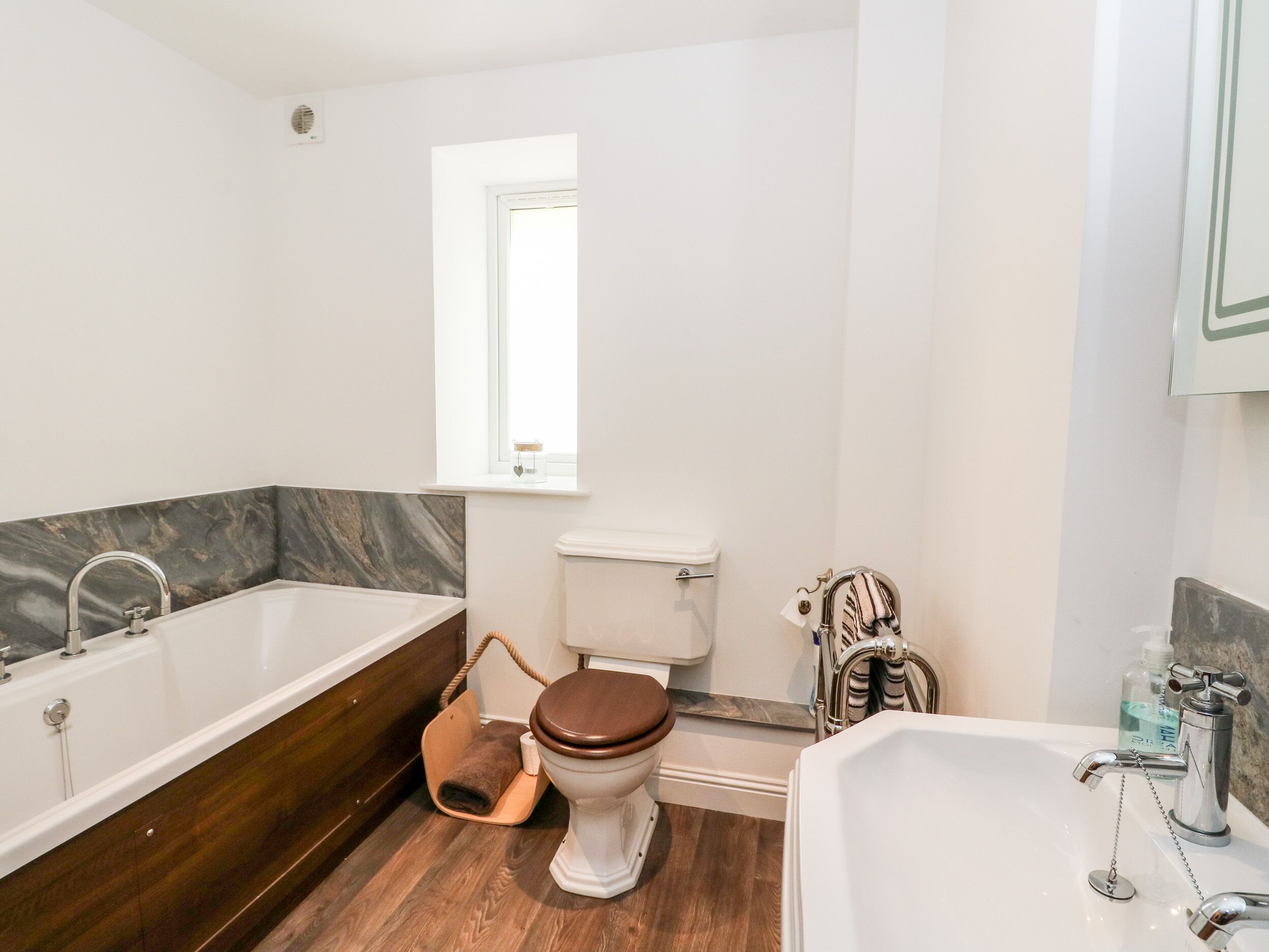 Een moderne badkamer met een bad, toilet en wastafel.