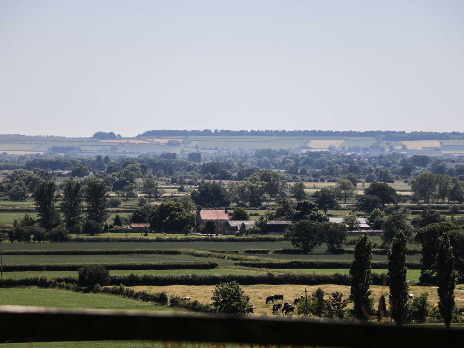 Un paysage rural avec des champs, des arbres et quelques bâtiments.