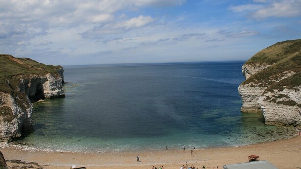 A coastal beach with cliffs, clear water, and a sandy shore. - Pebble Cottage Dunnscroft (Bridlington)