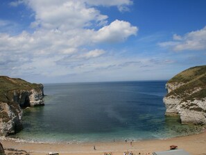 A coastal beach with cliffs and clear blue water. - Pebble Cottage Dunnscroft (Bridlington)