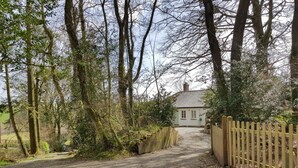 A gravel driveway leading to a white cottage with a wooden fence on one side. - Hedgelea (Okehampton)