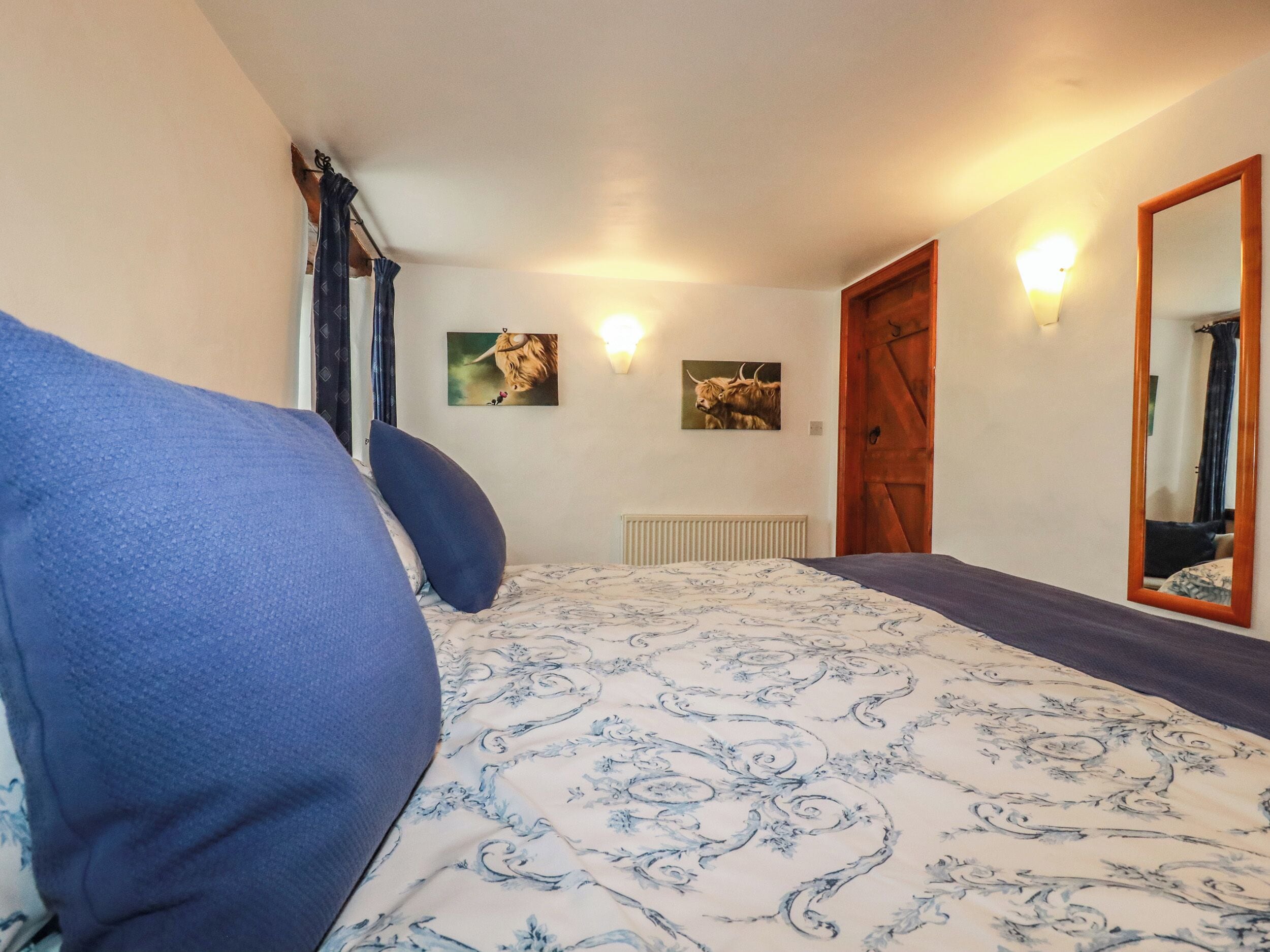 Un dormitorio con una cama, un espejo grande y dos luces fijadas a la pared.