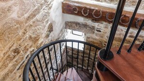 Una escalera de caracol con un fondo de pared de piedra y barandilla de madera.
