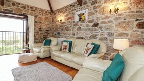 Una sala de estar acogedora con una pared de piedra, un conjunto de sofás y vistas a través de un ventanal.