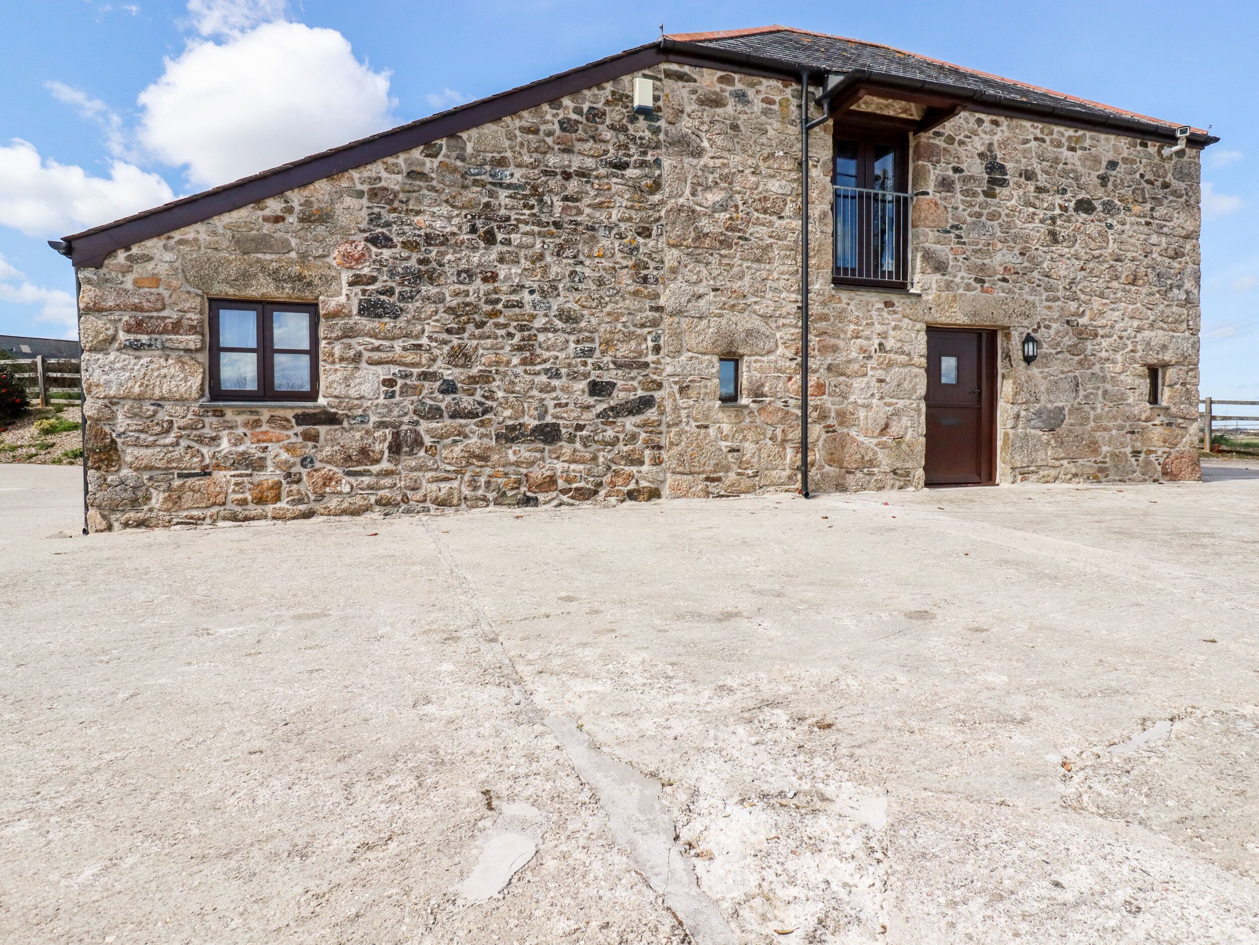 A stone building with a tiled roof, a door, and two windows.