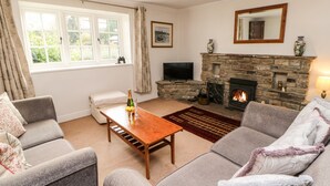 A living room with a stone fireplace, a television, and a sofa set. - Coverdale Cottage (Leyburn)