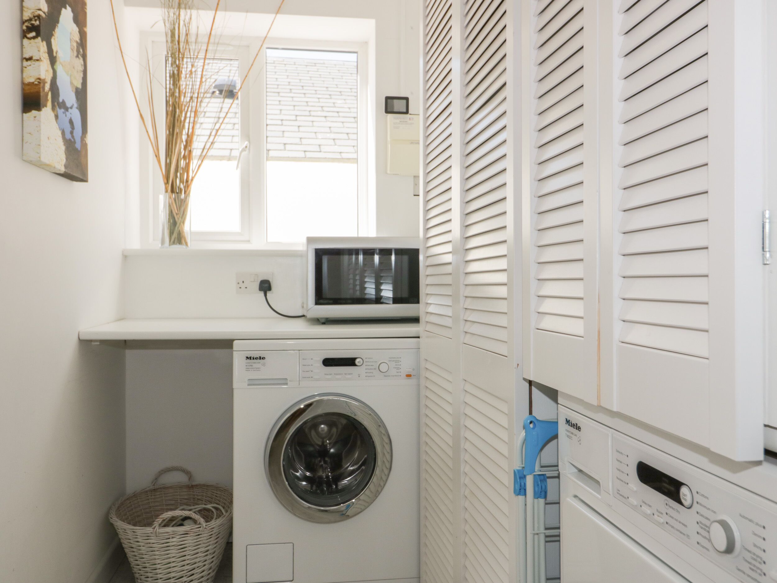 A compact laundry area with a washing machine, a microwave, and a dryer.