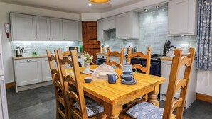 Een moderne keuken met witte kasten, een houten eettafel en een hangende pendel.