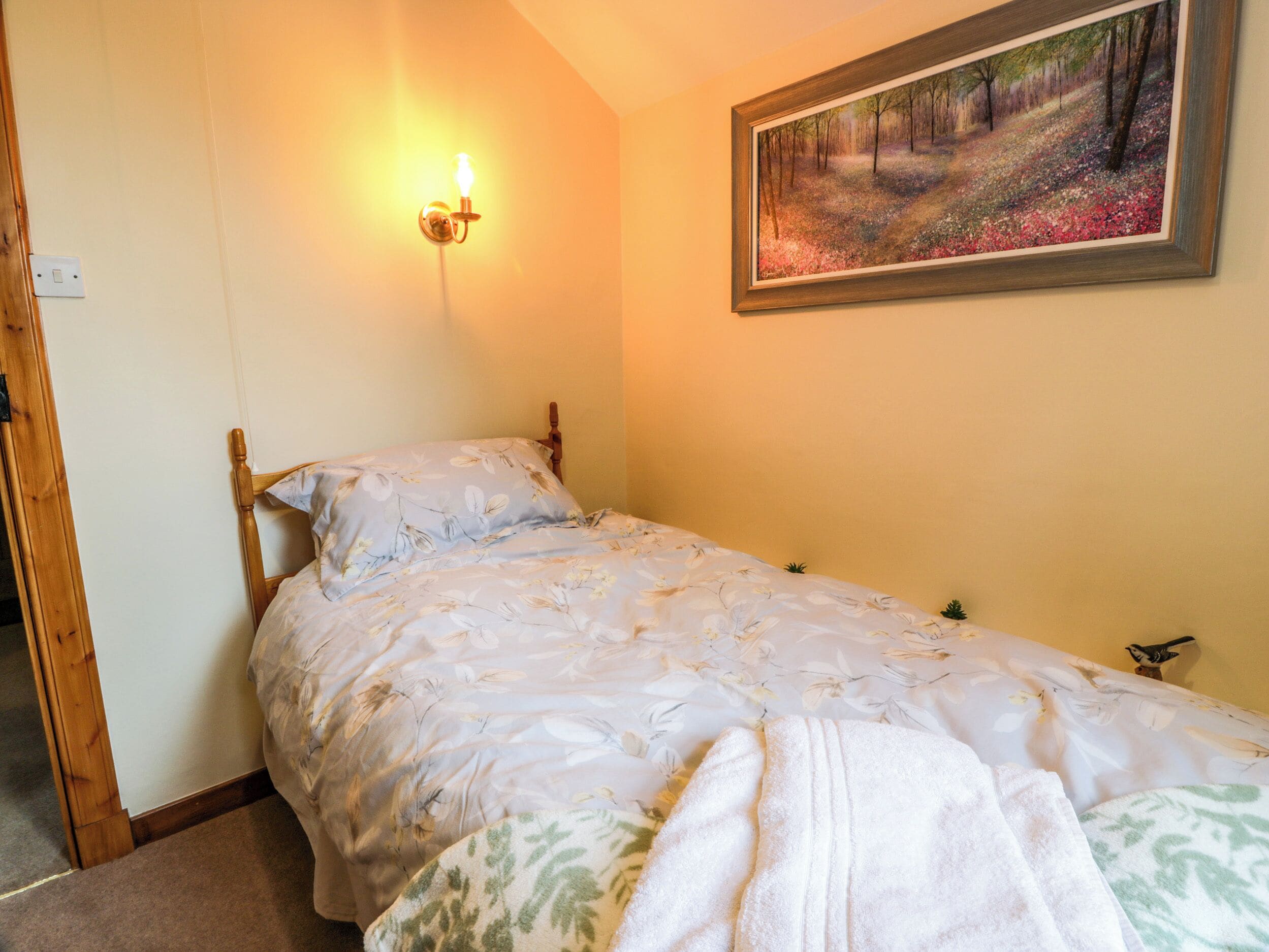 Un dormitorio con una cama, un cuadro en la pared y una lámpara de pared.