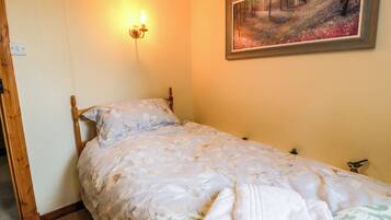 Un dormitorio con una cama, un cuadro en la pared y una lámpara de pared.