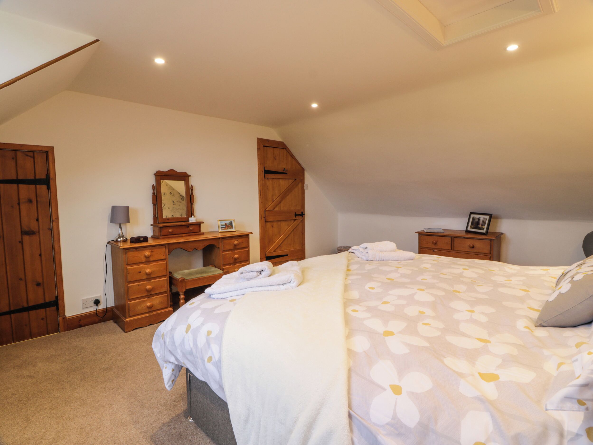 Une chambre à coucher avec un lit, une commode et un bureau doté d’un miroir.