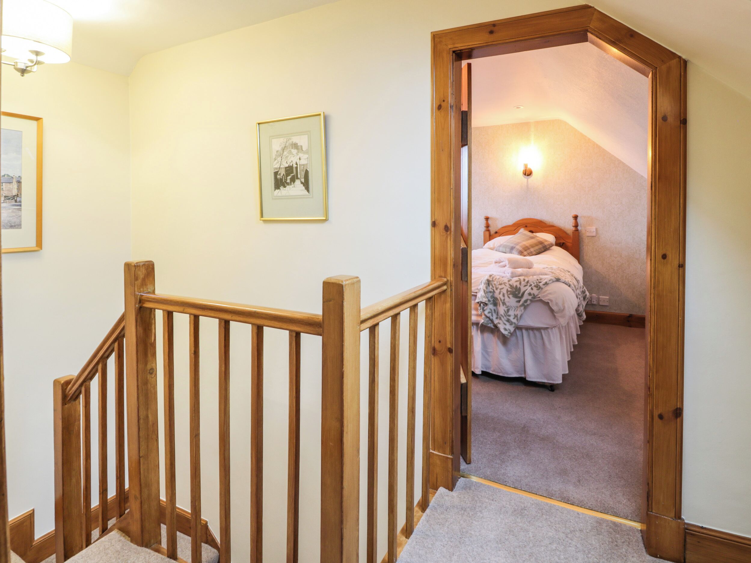 Une chambre à coucher avec un lit en bois, une table de chevet et une lampe fixée au mur.